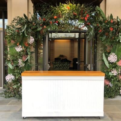 White beadboard bar in front of tropical flowers